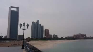 Daytime view of Abu Dhabi’s shoreline with the distinctive ADNOC Headquarters tower at left, alongside Etihad Towers and Emirates Palace across a calm waterfront.