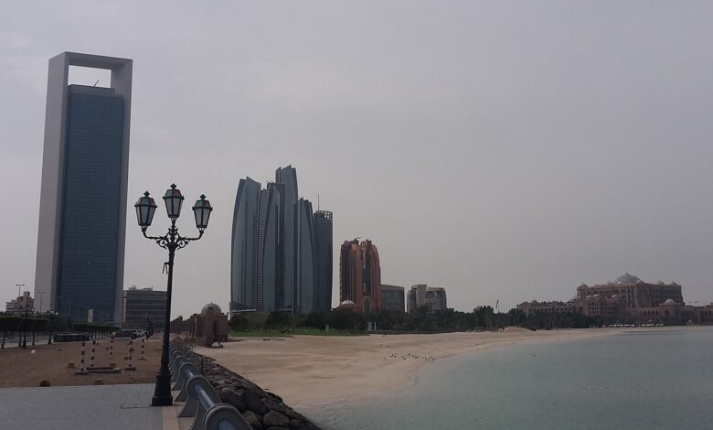 Daytime view of Abu Dhabi’s shoreline with the distinctive ADNOC Headquarters tower at left, alongside Etihad Towers and Emirates Palace across a calm waterfront.
